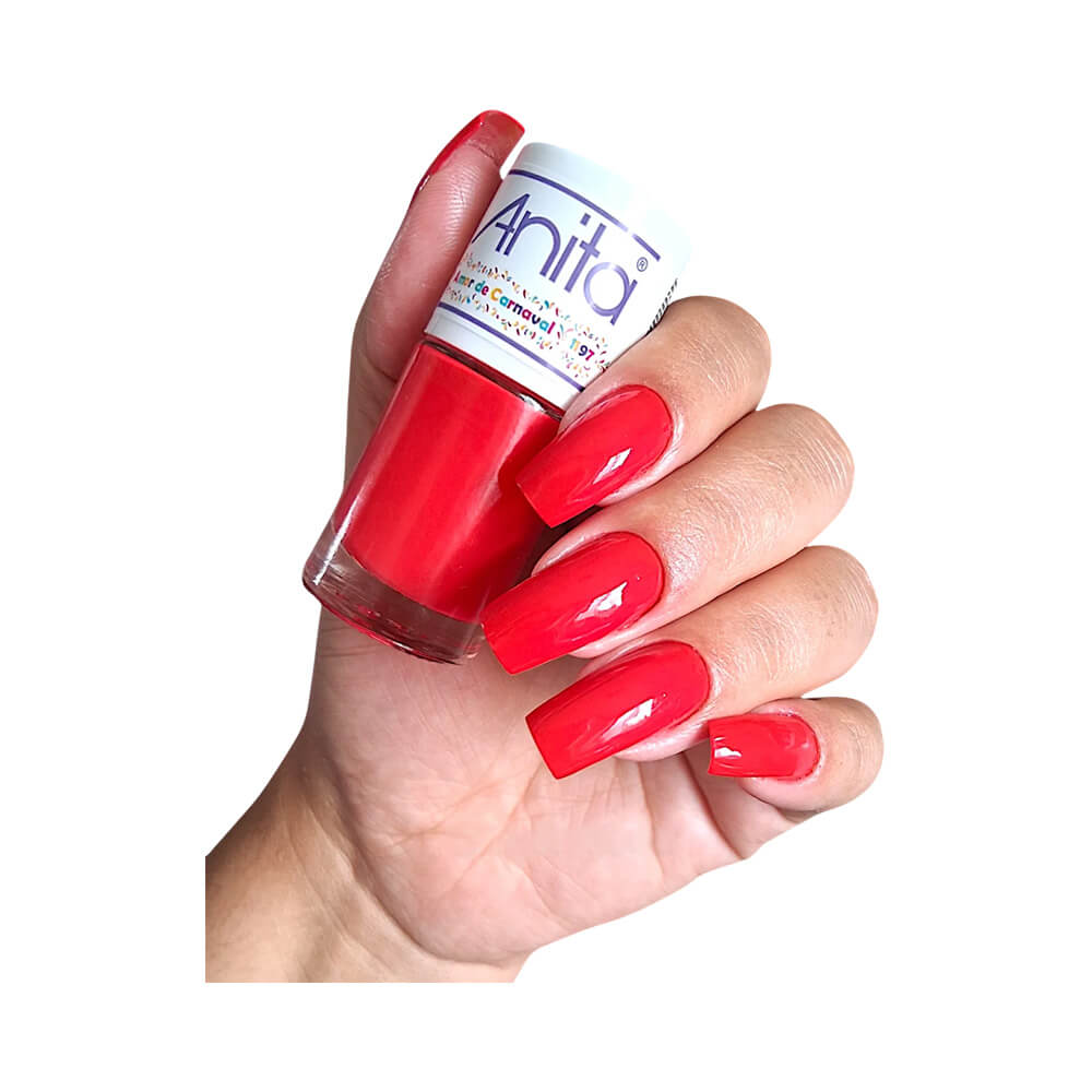 Mão segurando esmalte Anita Amor de Carnaval com unhas pintadas de vermelho cremoso